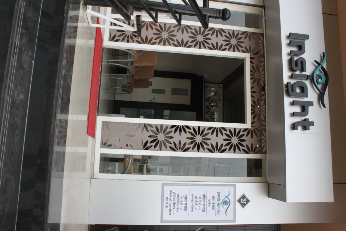 Street-level Insight Institute doorway with laser-cut floral framing and a department listing plate, photographed at an upward angle